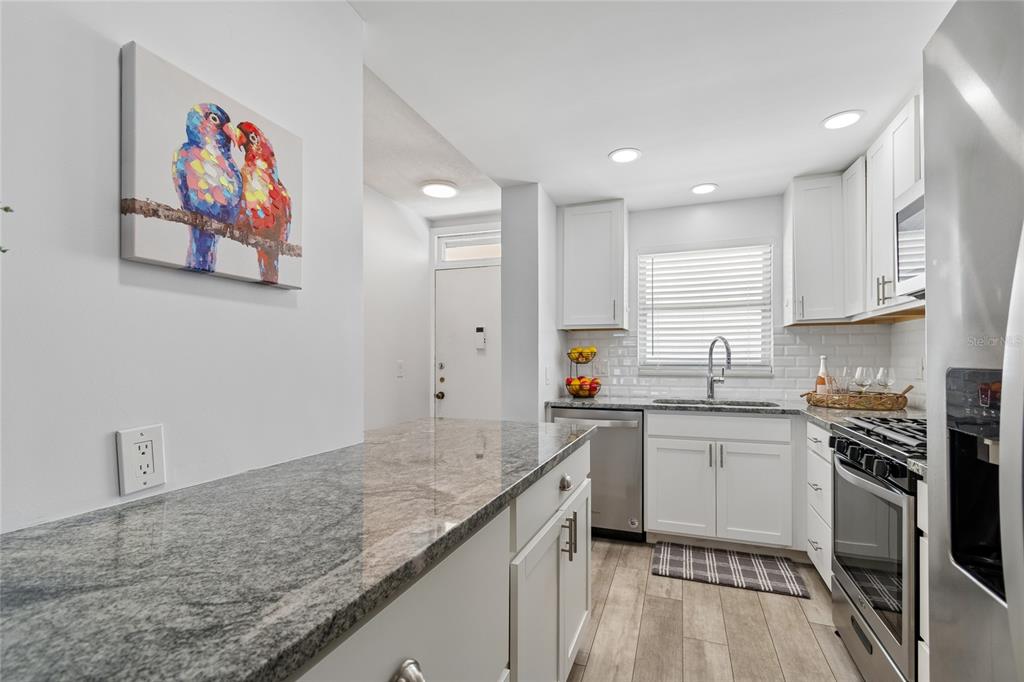 A kitchen features white cabinets, granite countertops, stainless steel appliances, and a breakfast bar — 5980 SHORE BOULEVARD S UNIT 909, GULFPORT, FL