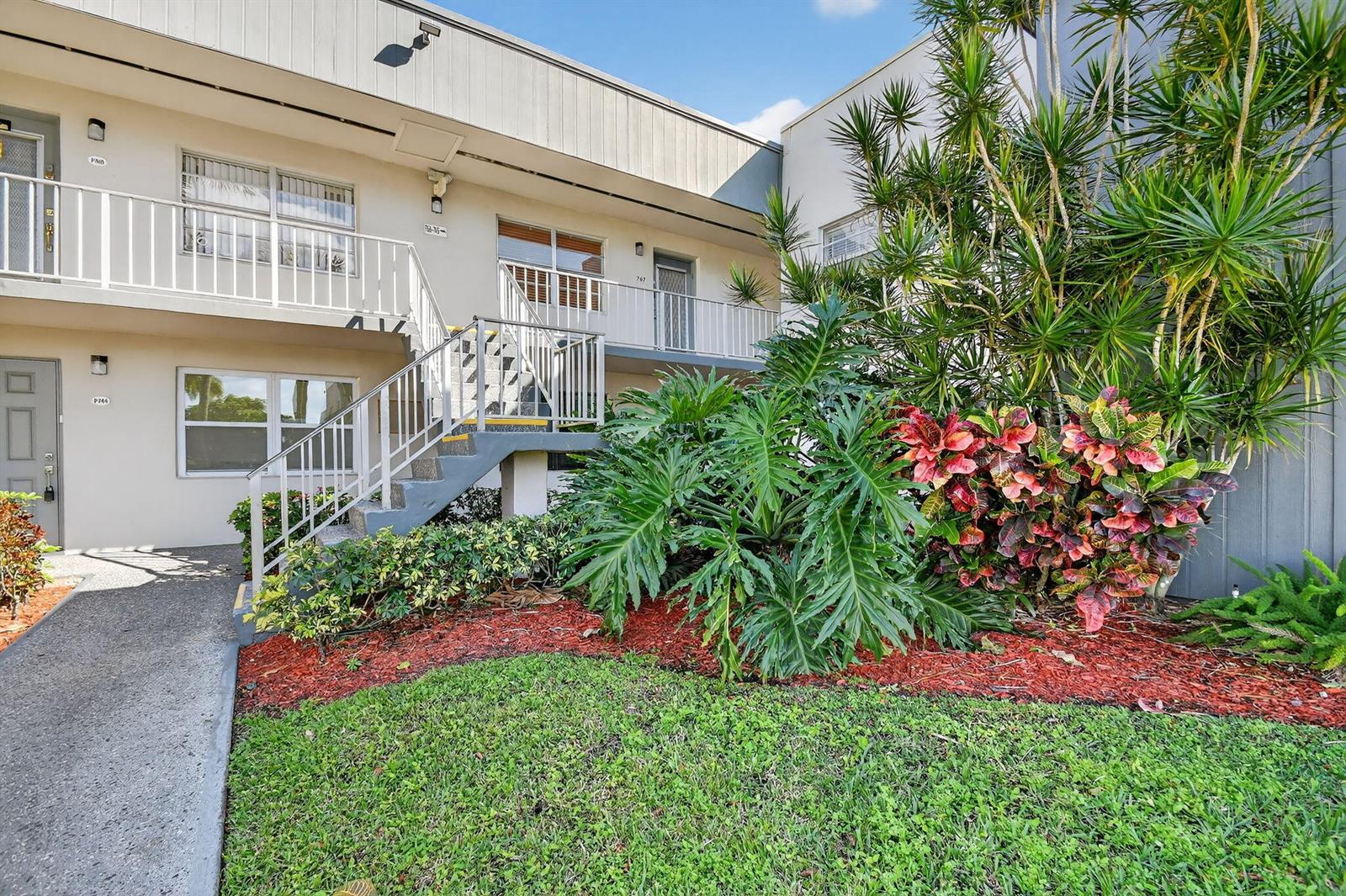 An exterior view of a two-story apartment building with stairs leading to the second floor — 743 Burgundy P, Delray Beach FL 33484, DELRAY BEACH, FL
