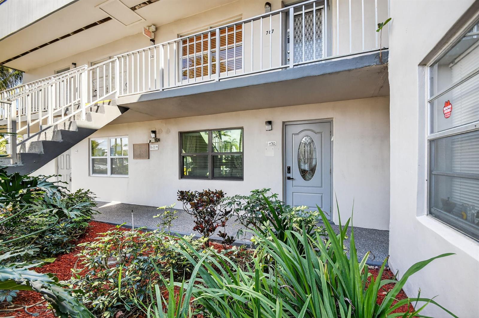 An exterior view of a two-story apartment building with a staircase and ground-level entrance — 743 Burgundy P, Delray Beach FL 33484, DELRAY BEACH, FL