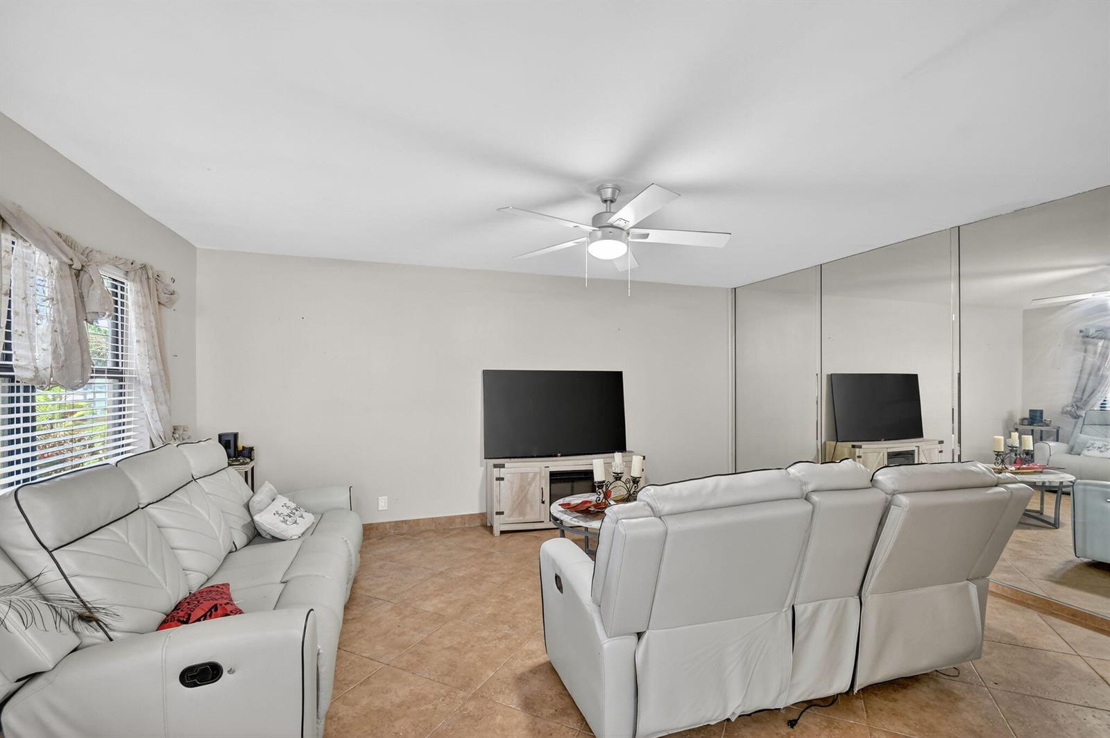 A living room features white leather sofas, tile flooring, a ceiling fan, and mirrored walls — 743 Burgundy P, Delray Beach FL 33484, DELRAY BEACH, FL