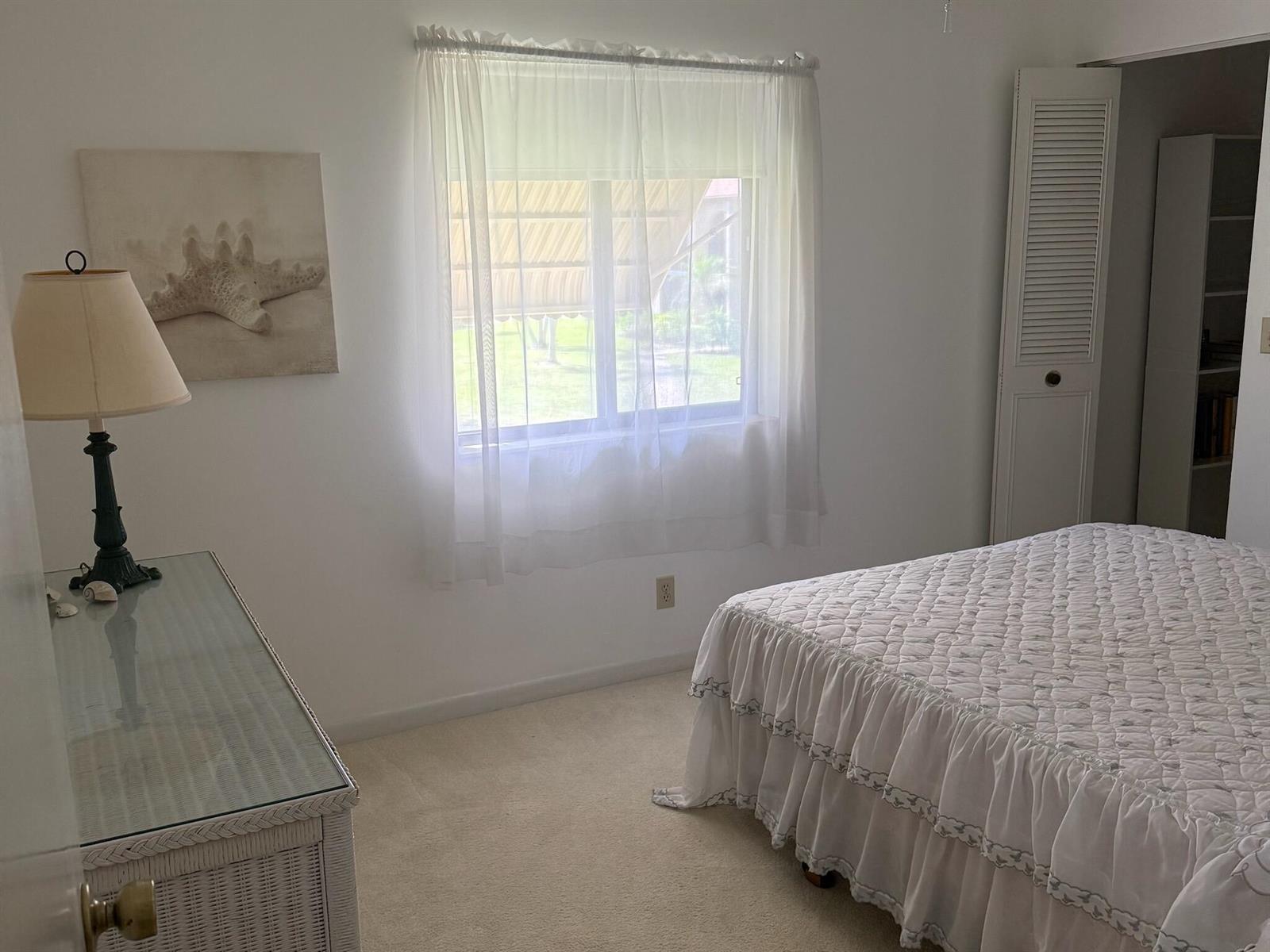 A bedroom with white walls, carpet, a bed with a ruffled quilt, and a window — 519 Shady Pine Way # A2, FL 33415, FL