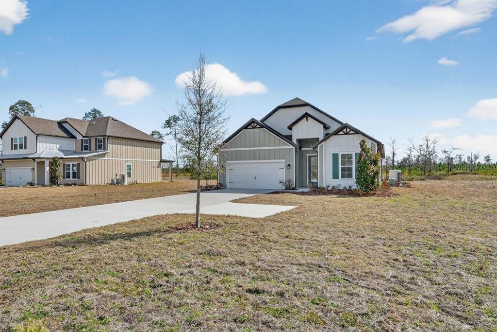 A single-story house with a two-car garage and a concrete driveway sits on a lot — 8495 FORD ROAD, BRYCEVILLE, FL