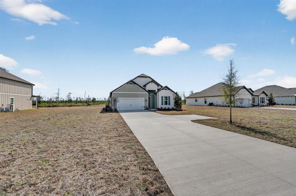 A single-story house with a white garage and driveway sits on a large, grassy lot — 8495 FORD ROAD, BRYCEVILLE, FL
