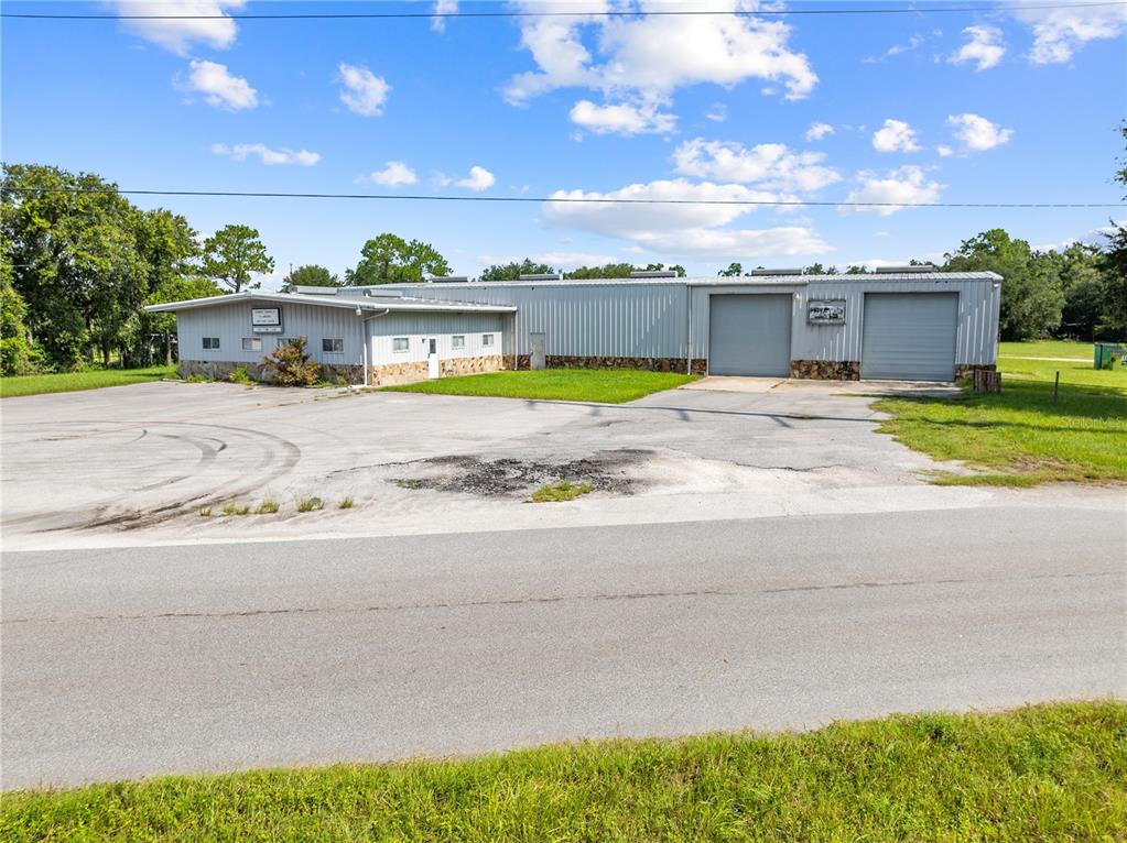 A single-story metal industrial building features two roll-up garage doors and a paved parking lot — 4411 TAMI LANE, KISSIMMEE, FL