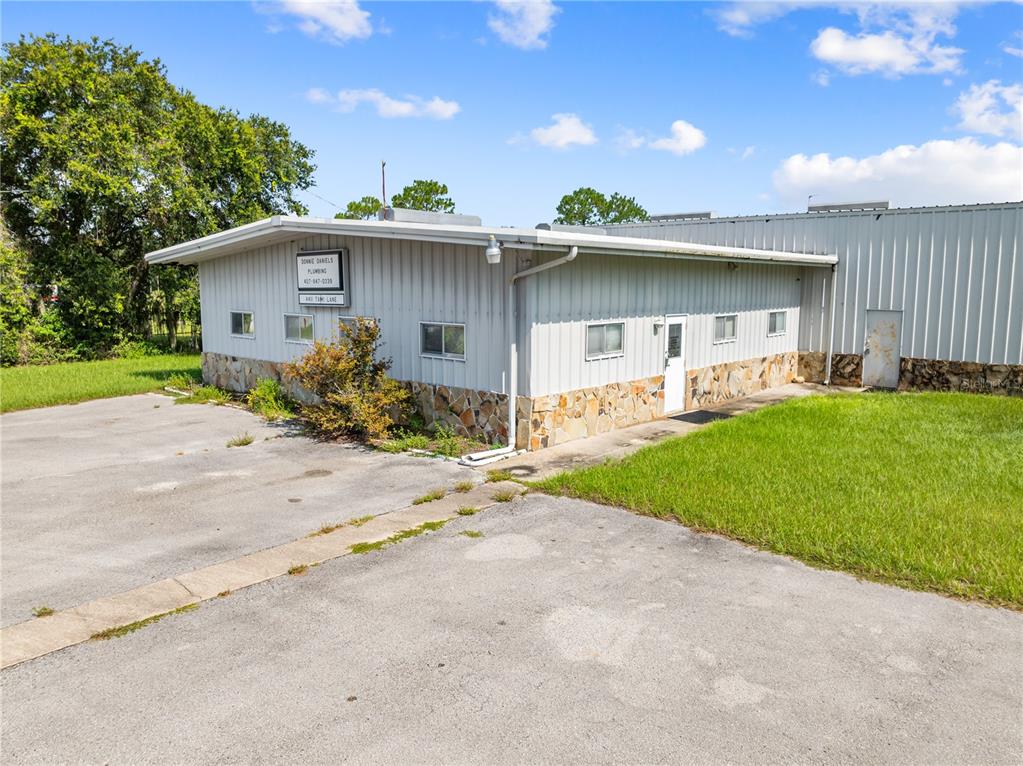 A single-story metal building with stone veneer siding sits on a paved lot — 4411 TAMI LANE, KISSIMMEE, FL