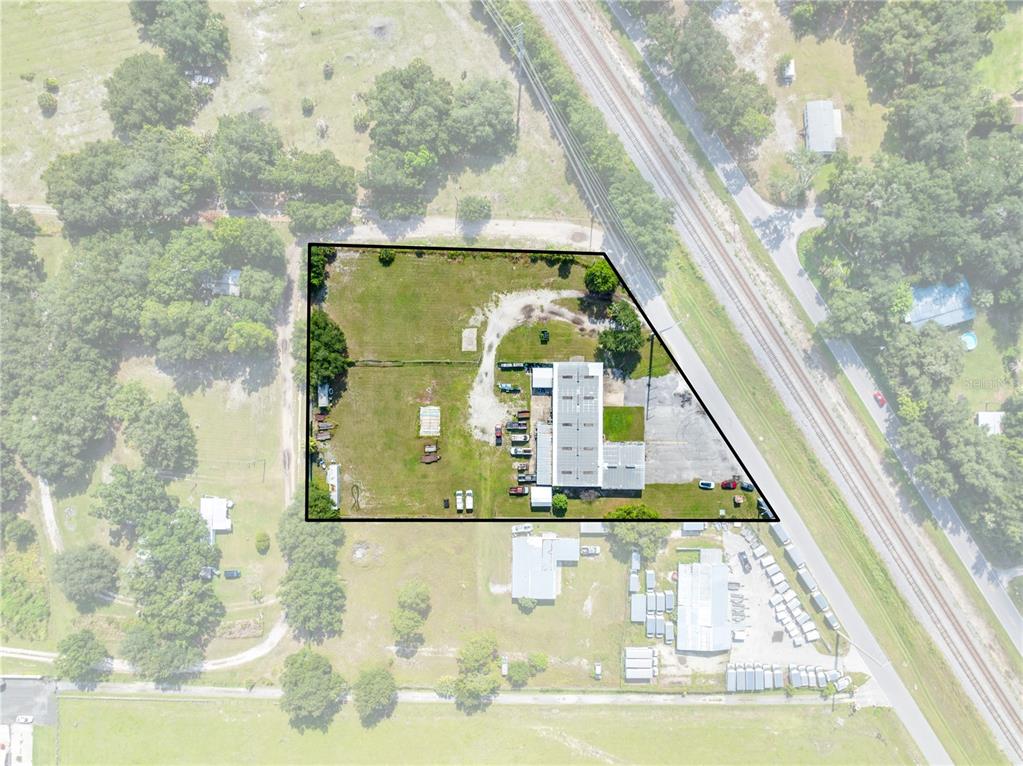 An aerial view shows a commercial property with a building and parking lot on a lot — 4411 TAMI LANE, KISSIMMEE, FL