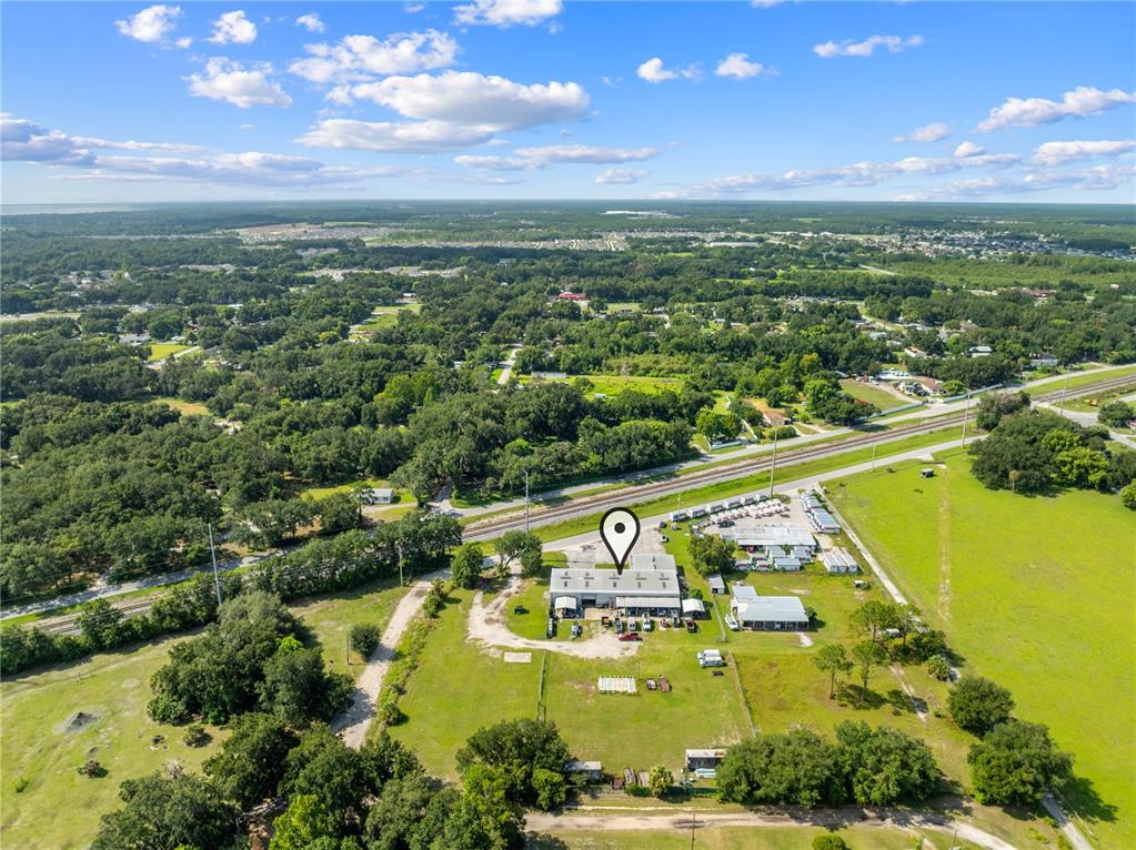 An aerial view shows a commercial building with a map pin located near railroad tracks — 4411 TAMI LANE, KISSIMMEE, FL