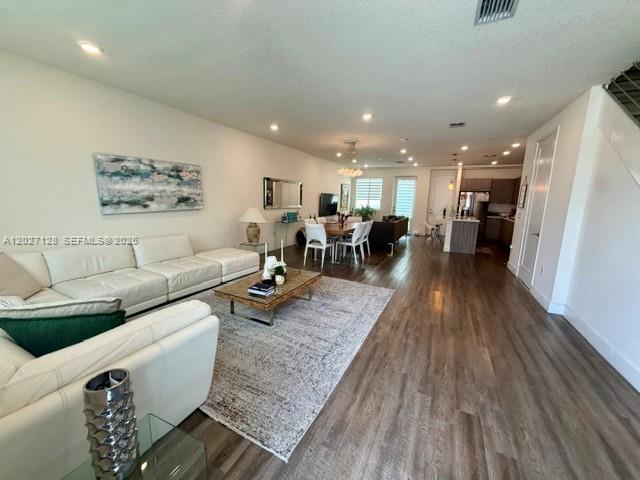 A living room features a white sectional sofa, a wooden coffee table, and wood flooring — DORAL, FL