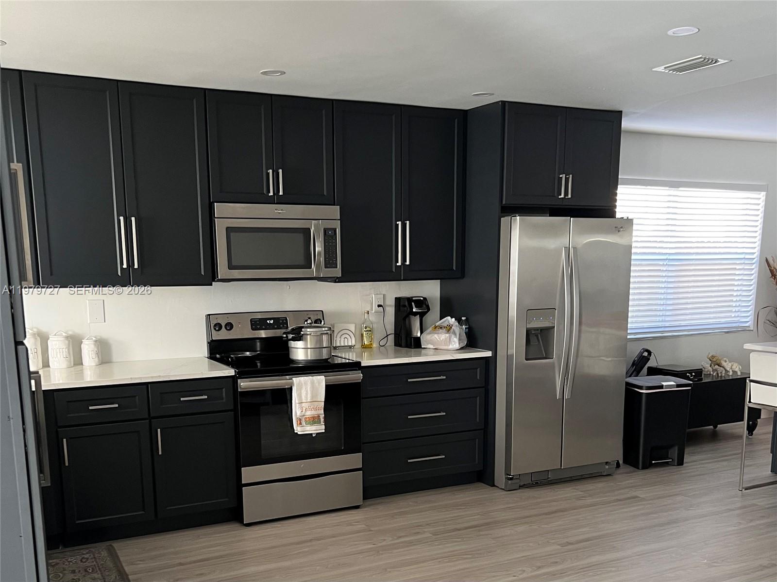 A kitchen features dark cabinets, stainless steel appliances, and white countertops with light flooring — 3771 NE 16th Ave, Pompano Beach FL 33064, POMPANO BEACH, FL
