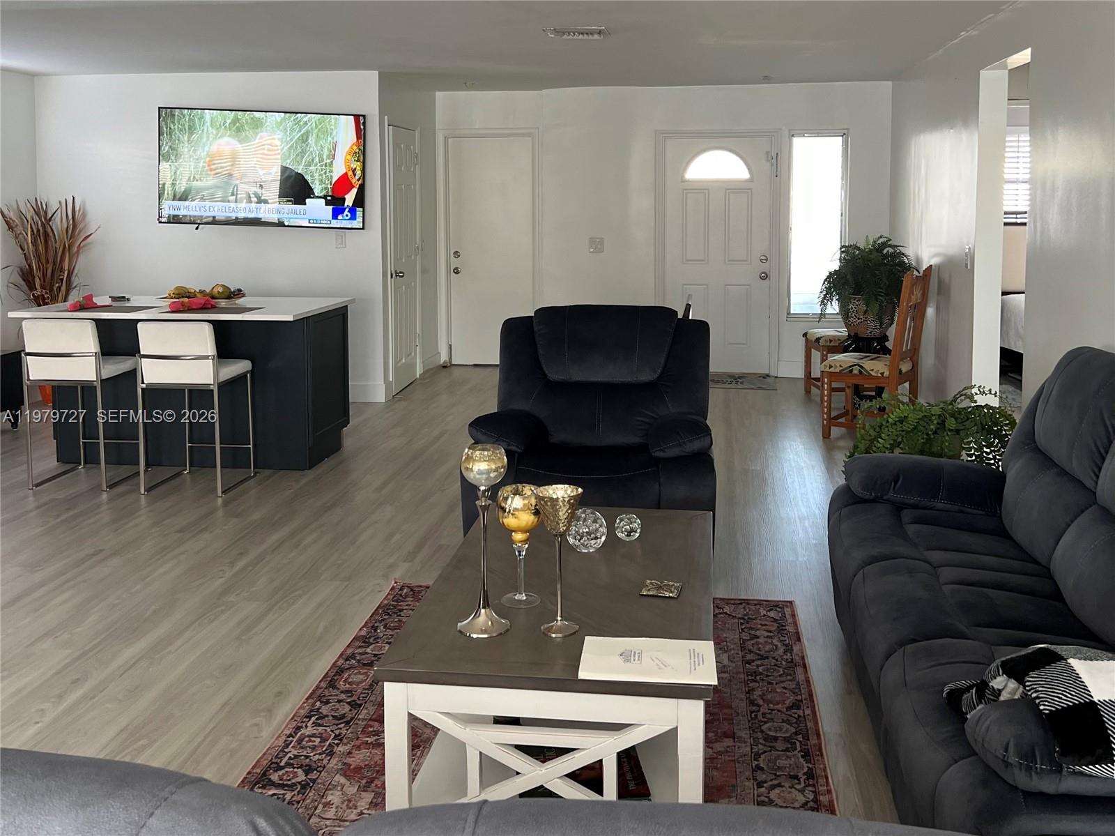 A living room features a dark recliner, a coffee table, and a kitchen island with stools — 3771 NE 16th Ave, Pompano Beach FL 33064, POMPANO BEACH, FL