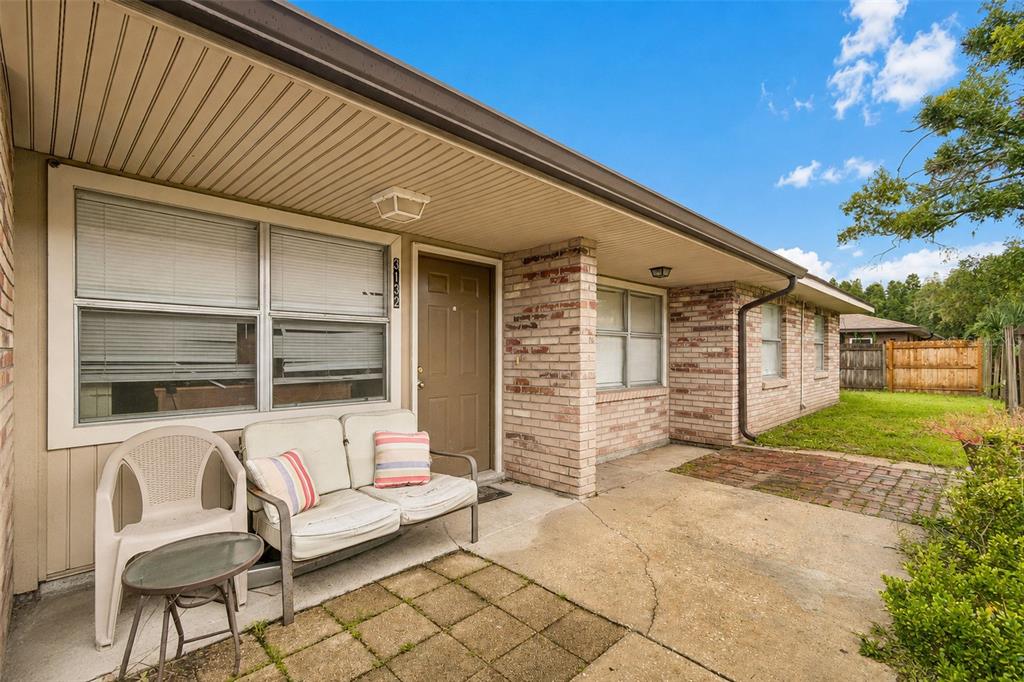 A brick and siding exterior features a concrete patio with outdoor seating and a front door — 3132 BLOOMINGDALE VILLAS COURT, BRANDON, FL