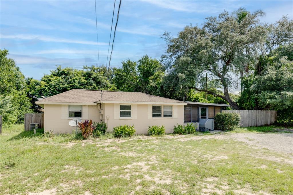 A single-story house with a tan exterior, a brown roof, and a gravel yard — 4181 CHESTNUT DRIVE, MOUNT DORA, FL