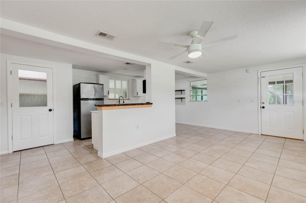 A kitchen with a breakfast bar and tile flooring opens into a living area — 4181 CHESTNUT DRIVE, MOUNT DORA, FL