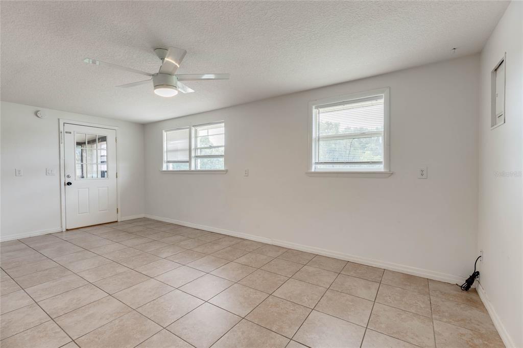 An empty room with white walls, tile flooring, a ceiling fan, and two windows — 4181 CHESTNUT DRIVE, MOUNT DORA, FL