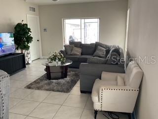 A living room features a grey sectional sofa, a white armchair, and a glass coffee table — 3547 FORSTER AVENUE, LEESBURG, FL