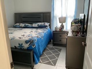 A bedroom features a bed with a blue floral quilt, a nightstand, and a dresser — 3547 FORSTER AVENUE, LEESBURG, FL