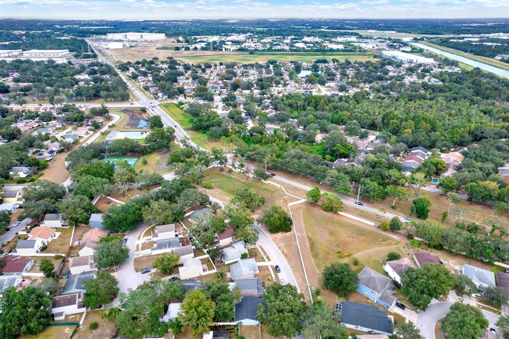 An aerial view shows a suburban neighborhood with houses, trees, and a nearby road — 7502 GADSDEN DRIVE, TEMPLE TERRACE, FL