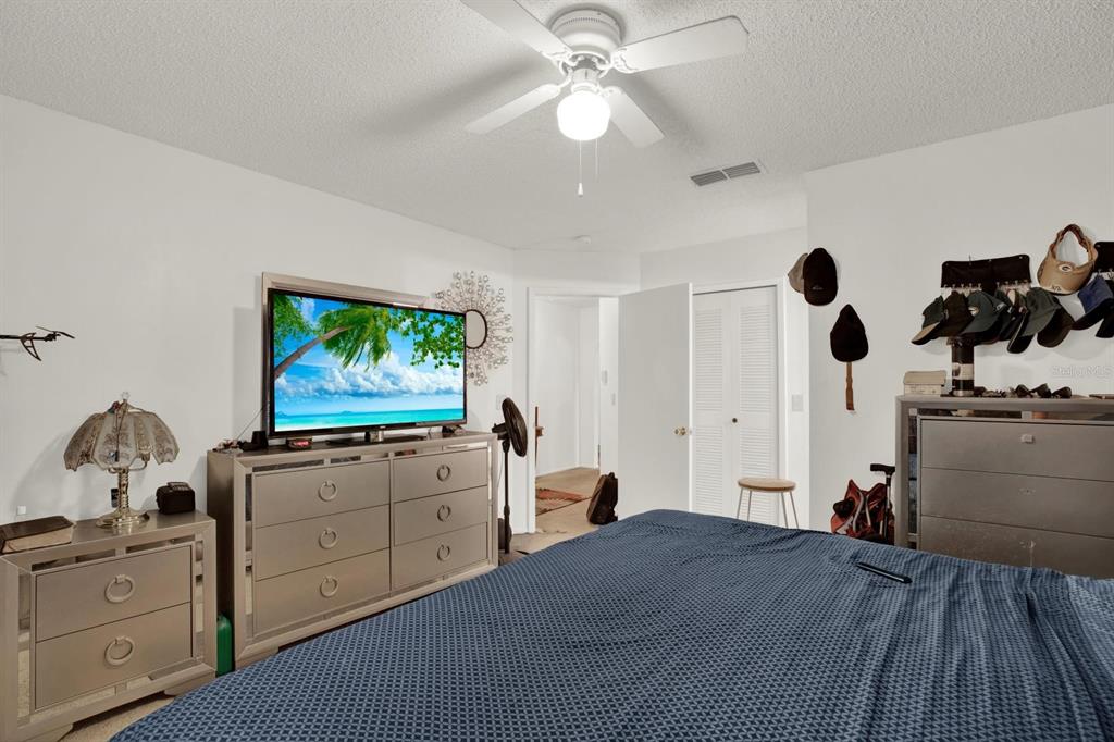 A bedroom features a bed, two mirrored dressers, a television, and a ceiling fan — 7502 GADSDEN DRIVE, TEMPLE TERRACE, FL