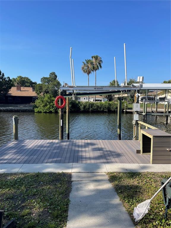 A wooden dock with a boat lift sits along a canal under a clear sky — 11711 W BAYSHORE DRIVE, CRYSTAL RIVER, FL