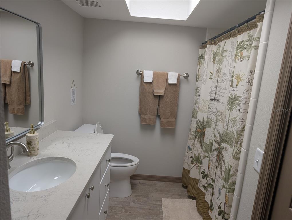 A bathroom features a white vanity with a stone countertop, a toilet, and a shower — 11711 W BAYSHORE DRIVE, CRYSTAL RIVER, FL