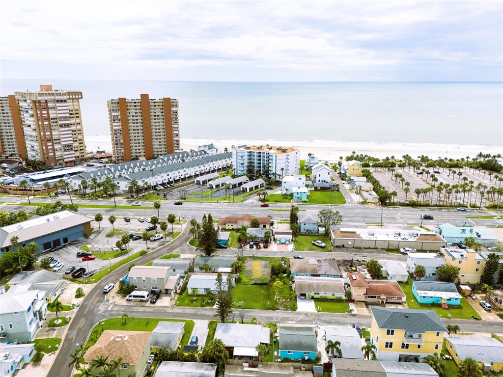 An aerial view shows a coastal neighborhood with houses, parking lots, and high-rise buildings — 18005 1ST STREET E, ST PETERSBURG, FL