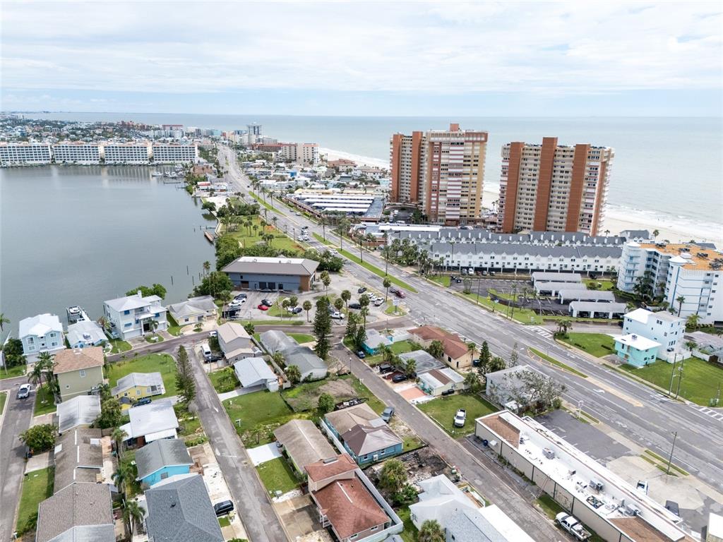 An aerial view shows a coastal neighborhood with houses, a road, and high-rise buildings — 18005 1ST STREET E, ST PETERSBURG, FL