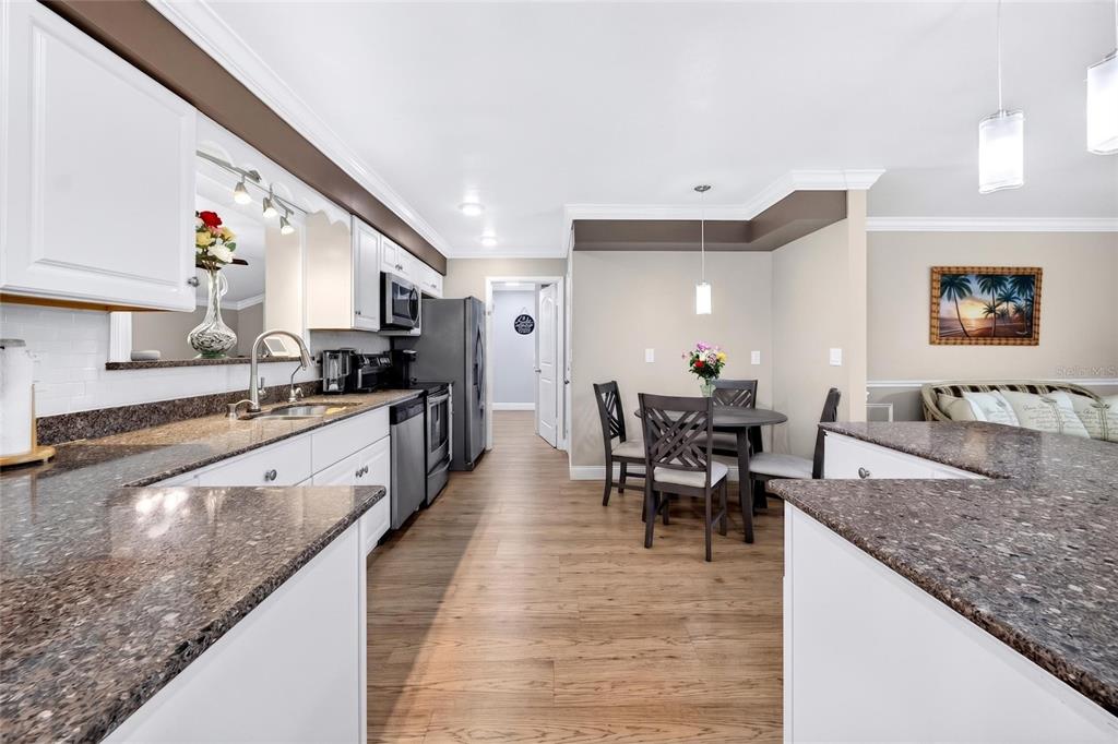 A kitchen with white cabinets, granite countertops, and a dining area with a round table — 1743 COUNCIL DRIVE, SUN CITY CENTER, FL