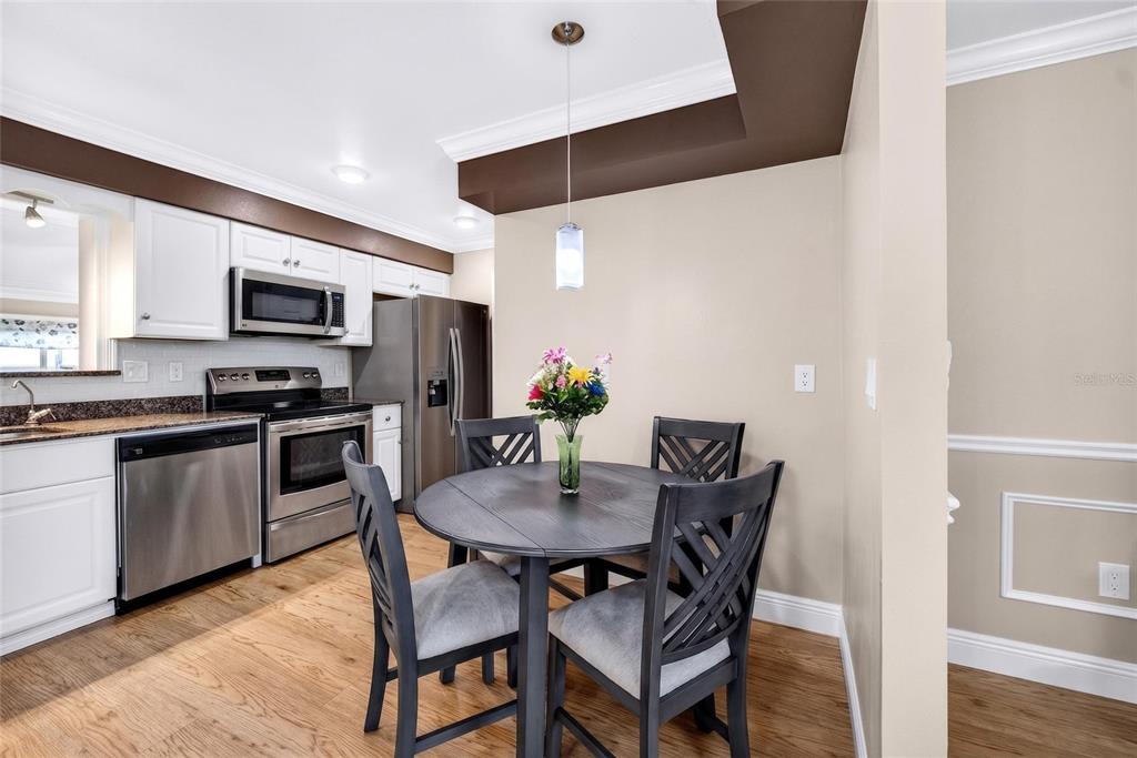 A kitchen with white cabinets, stainless steel appliances, and a small round dining table — 1743 COUNCIL DRIVE, SUN CITY CENTER, FL