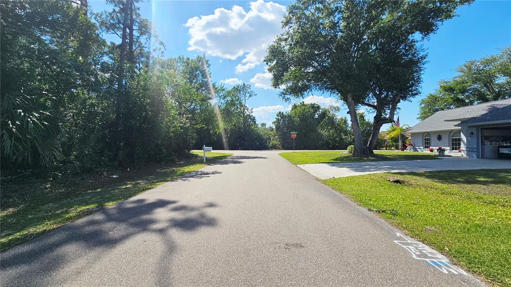 A paved residential street leads toward a stop sign near a house with a driveway — 23039 & 23047 AUGUST LOTS 24 & 25 AVENUE, PORT CHARLOTTE, FL