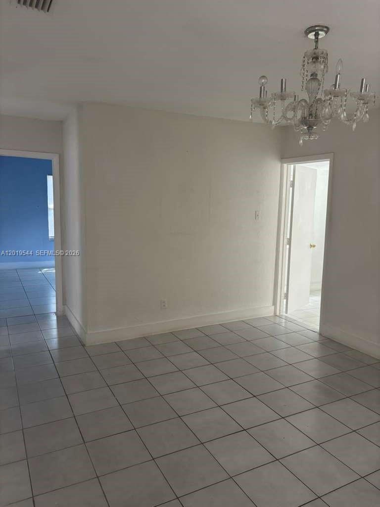 A room with white walls, light-colored floor tiles, and a crystal chandelier — 1447 NW 98th St # 0, Miami FL 33147, MIAMI, FL