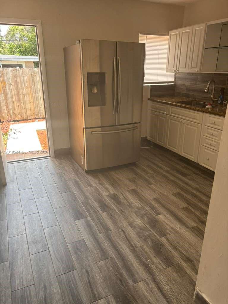 A kitchen features stainless steel appliances, white cabinets, granite countertops, and wood-look tile flooring — 1447 NW 98th St # 0, Miami FL 33147, MIAMI, FL