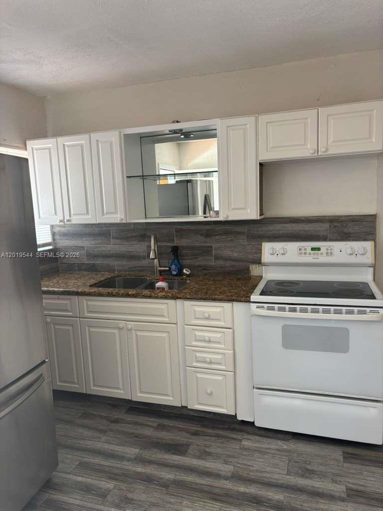 A kitchen features white cabinets, a granite countertop, a stainless steel sink, and white appliances — 1447 NW 98th St # 0, Miami FL 33147, MIAMI, FL