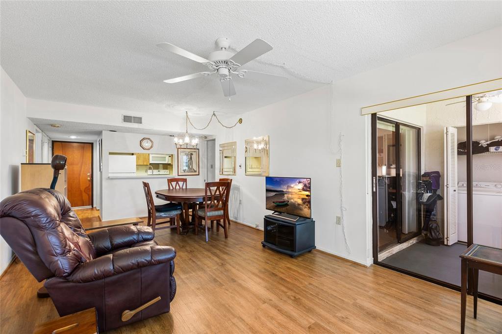 A living and dining area features wood-look flooring, a ceiling fan, and a sliding glass door — 2587 COUNTRYSIDE BOULEVARD UNIT 6110, CLEARWATER, FL