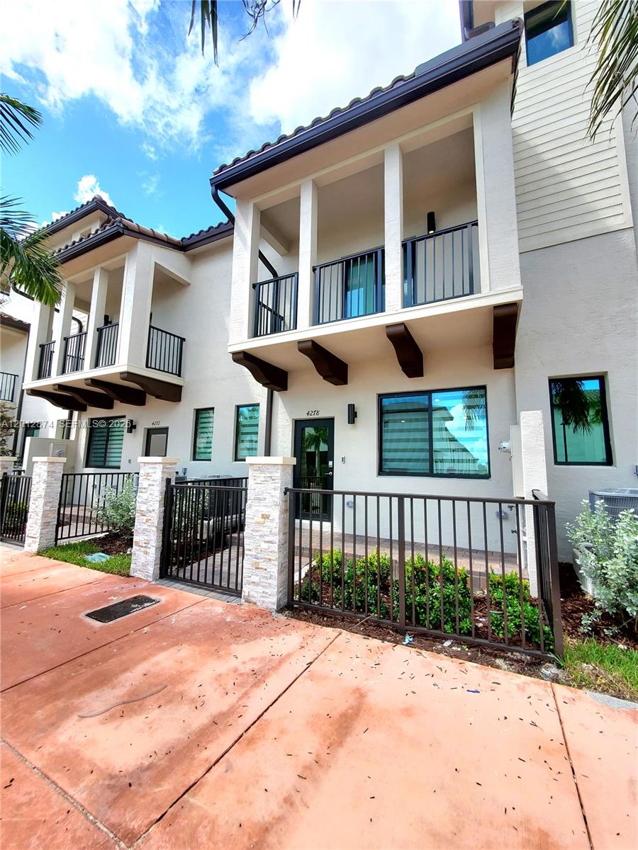 A two-story townhouse exterior features a gated front patio, a balcony, and stone-accented pillars — 4278 NW 82nd Ave # 4278, Doral FL 33166, DORAL, FL
