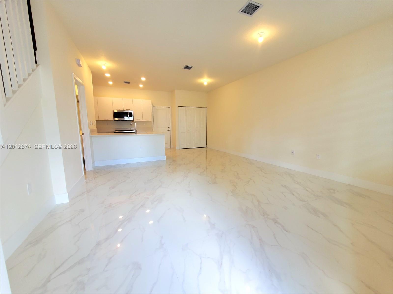 An open-concept living area features white marble-look tile flooring and a kitchen with white cabinetry — 4278 NW 82nd Ave # 4278, Doral FL 33166, DORAL, FL