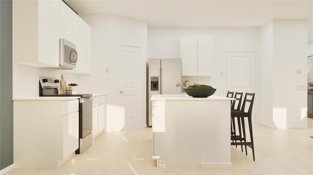 A modern kitchen features white cabinetry, stainless steel appliances, a center island, and light flooring — 3043 GRANITE RIDGE AVENUE, MINNEOLA, FL
