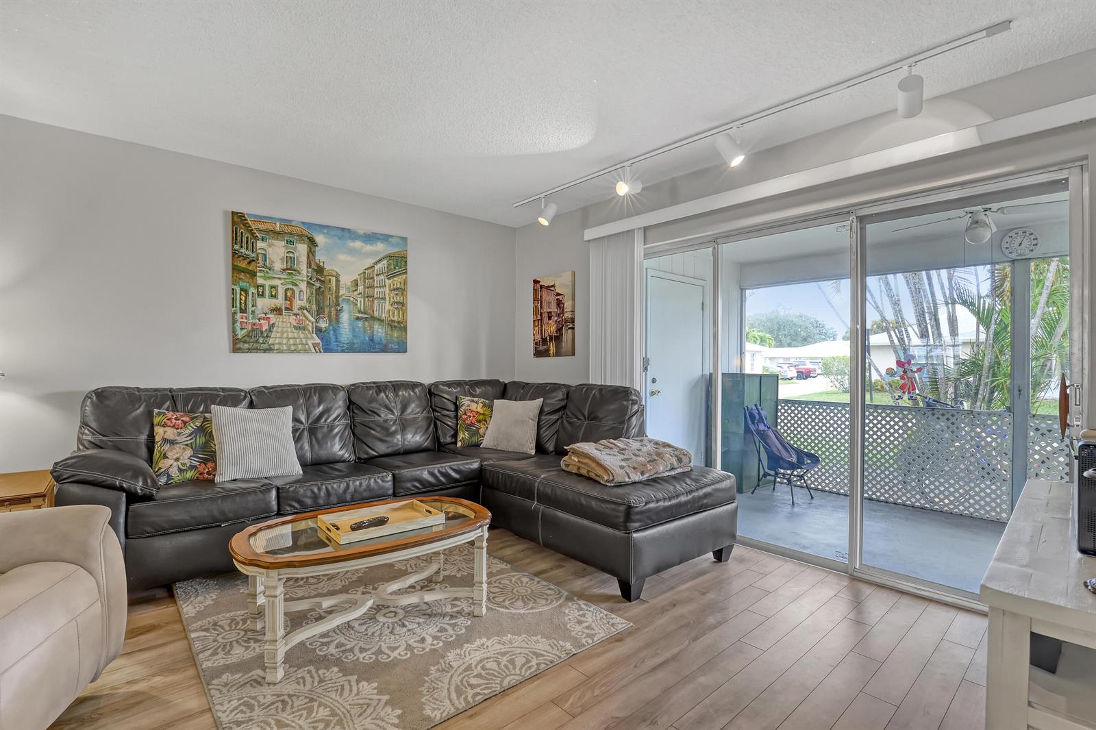 A living room features a dark leather sectional, a coffee table, and sliding glass doors — 553 Covered Bridge Boulevard, Lake Worth FL 33467, LAKE WORTH, FL