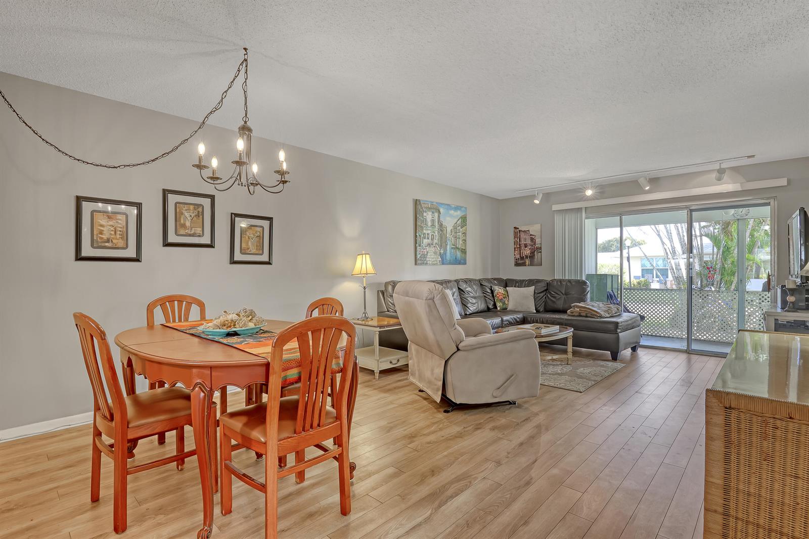 A living and dining room with wood-look flooring, a chandelier, and a sliding glass door — 553 Covered Bridge Boulevard, Lake Worth FL 33467, LAKE WORTH, FL