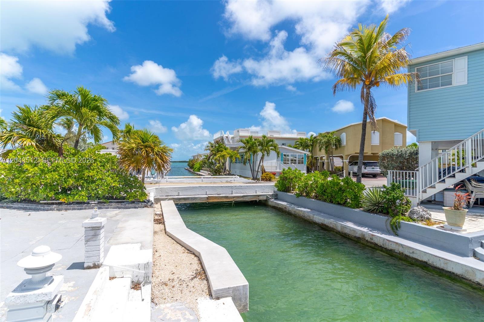 A canal flows between residential properties with palm trees under a bright blue sky — 65821 Overseas Hwy #291, Long Key FL 33001, LONG KEY, FL