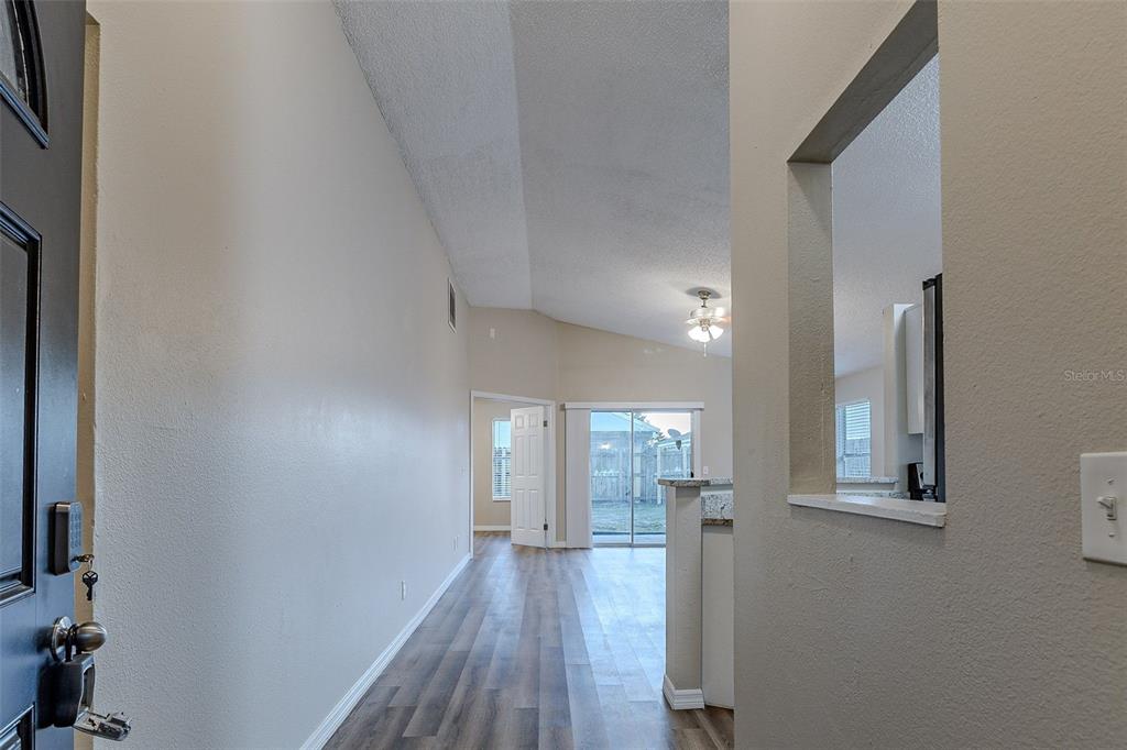 A view from an entryway looking into a living area with wood-look flooring and vaulted ceilings — 5436 WOOD CROSSING STREET, ORLANDO, FL