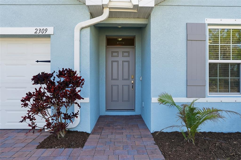 The exterior of a light blue house features a gray front door and a walkway — 2309 PILGER AVENUE, NORTH PORT, FL