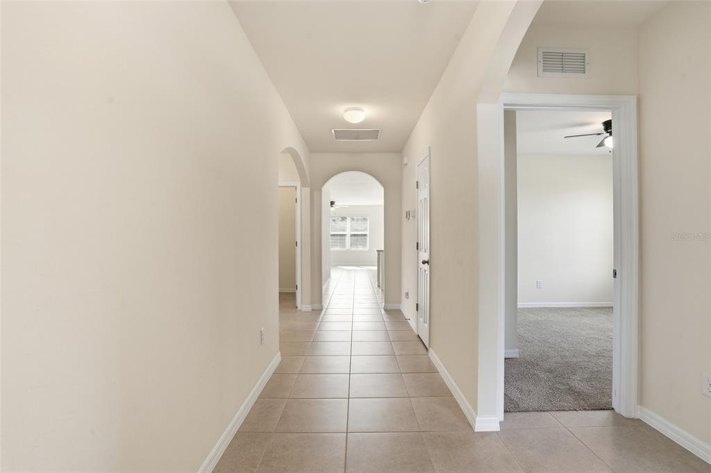 A tiled hallway leads through an arched doorway toward a carpeted room and window — 2309 PILGER AVENUE, NORTH PORT, FL