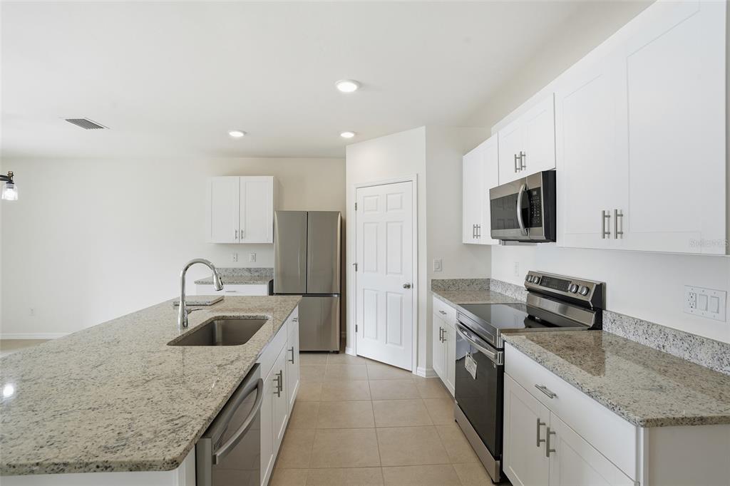 A kitchen features white cabinets, granite countertops, stainless steel appliances, and a central island — 2309 PILGER AVENUE, NORTH PORT, FL