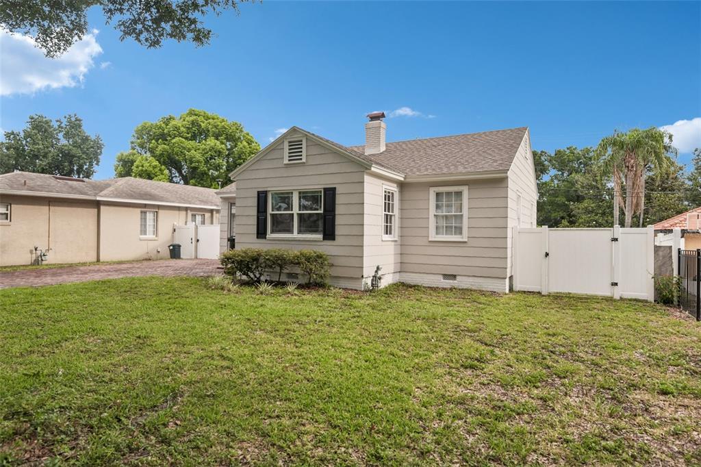 A beige, single-story house with a chimney and white fence stands on a grassy lot — 624 KERNEYWOOD STREET, LAKELAND, FL