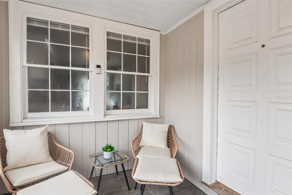 A covered porch features two wicker chairs with cushions, a small glass table, and windows — 624 KERNEYWOOD STREET, LAKELAND, FL