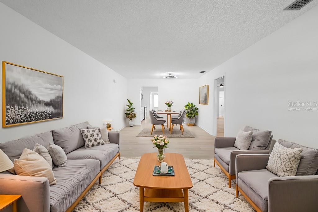 This living and dining area features light wood-look flooring, white walls, and virtual staging — 11200 102ND AVENUE UNIT 74, SEMINOLE, FL
