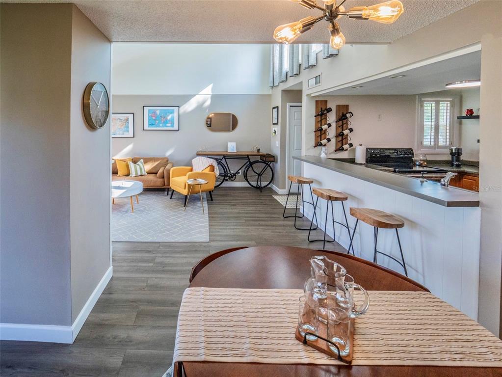 A view from a dining area looking into a living room with a kitchen breakfast bar — 1051 S HIGHLAND STREET UNIT 7E, MOUNT DORA, FL