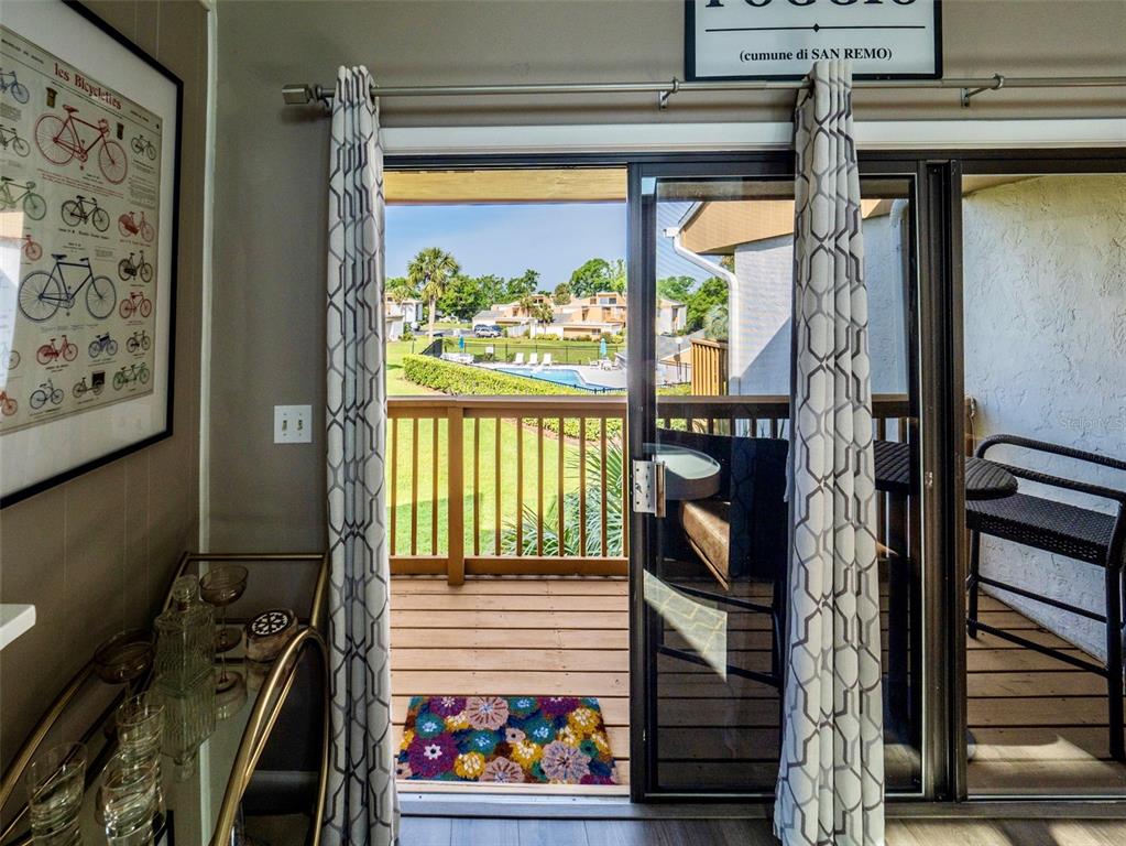 A view from an interior room through a sliding glass door onto a wooden balcony — 1051 S HIGHLAND STREET UNIT 7E, MOUNT DORA, FL