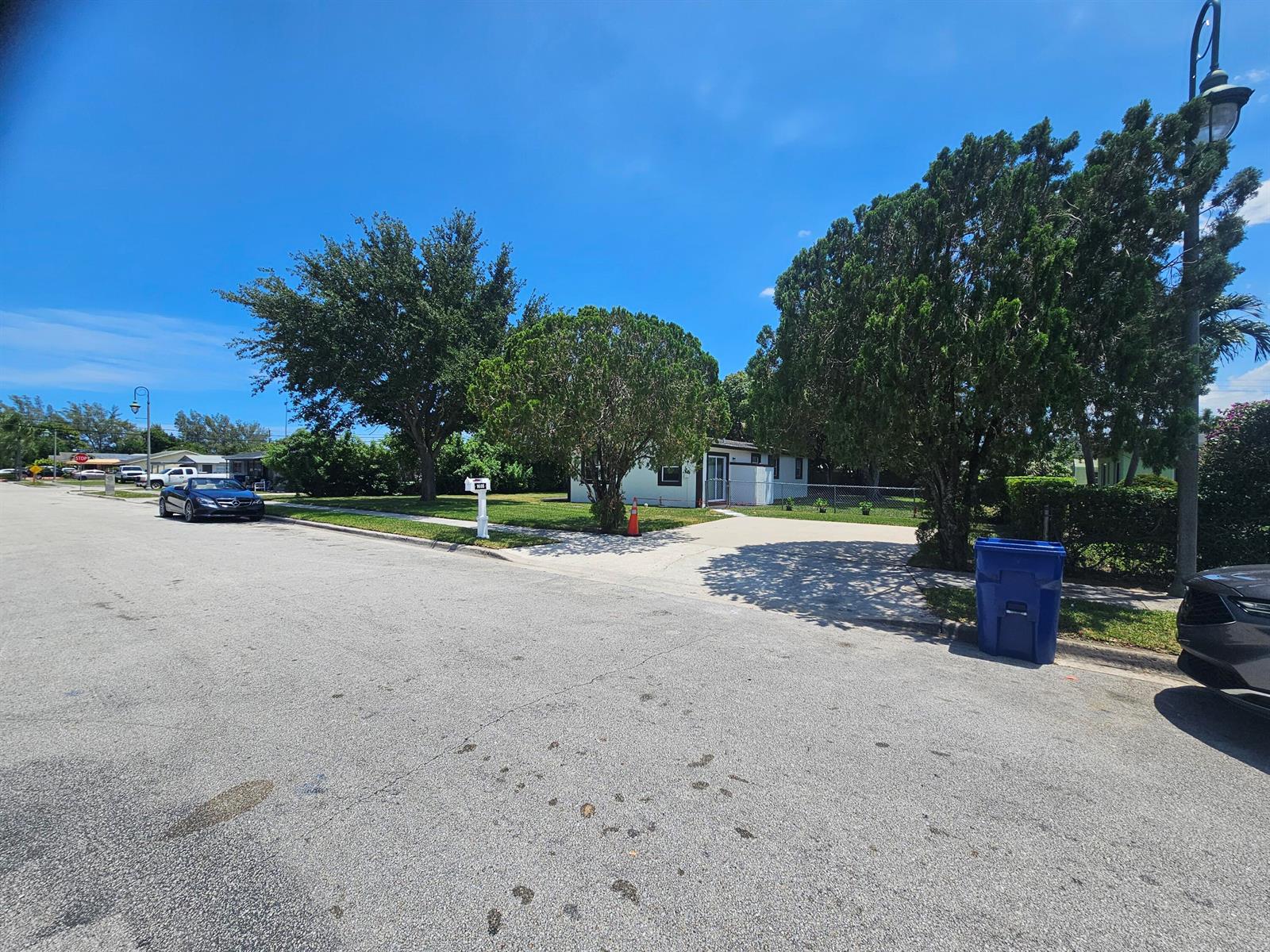 A single-story house with a driveway and trees sits along a residential street — 1605 W 10th Street, Riviera Beach FL 33404, RIVIERA BEACH, FL
