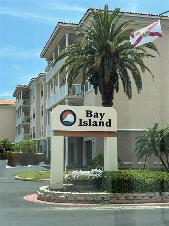 A sign for Bay Island stands in front of a multi-story apartment building with palm trees — 7645 SUN ISLAND DRIVE S UNIT 101, SOUTH PASADENA, FL